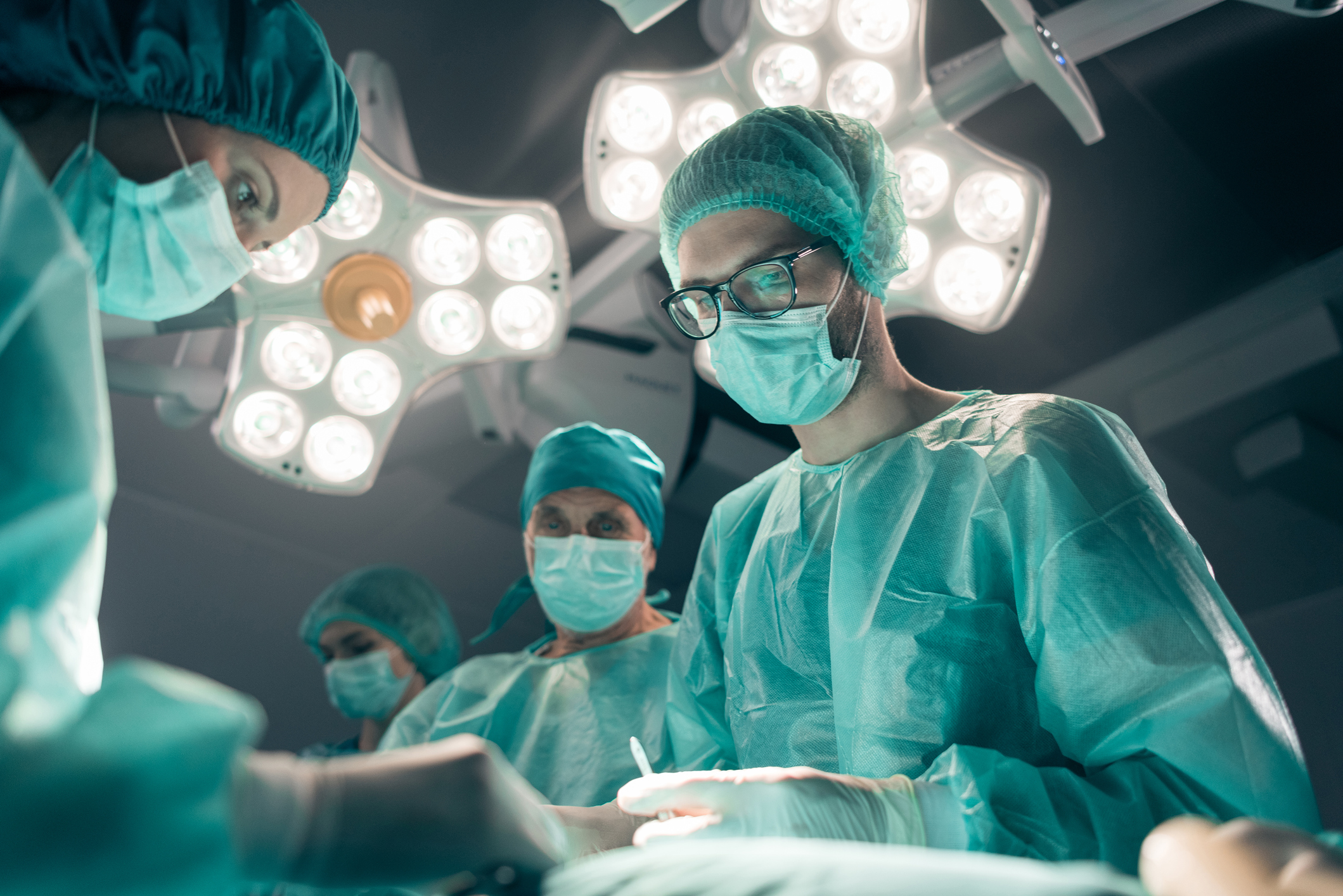 Focused and concentrated young surgeon performing surgical operation in modern operating room